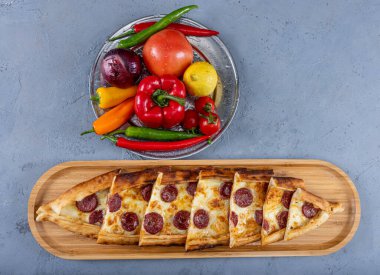 Biberli ve peynirli Türk pide tabağı. Geleneksel Türk pidesi. (pepperonili pide) ahşap serviste. Türkçe adı: Sucuklu pide.