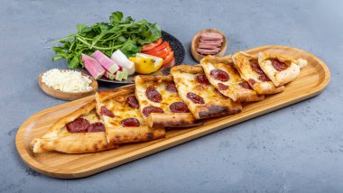 Biberli ve peynirli Türk pide tabağı. Geleneksel Türk pidesi. (pepperonili pide) ahşap serviste. Türkçe adı: Sucuklu pide.