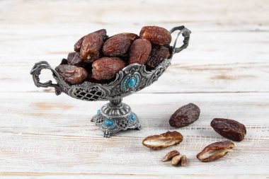 Tahta arka planda eski gümüş tabakta meyve ve zamzam suyu var. Ramazan iftar yemeği. Kurumuş tarihli Ramazan kareemi ve orjinal metal zamzam su testisi, kutsal ay konsepti..