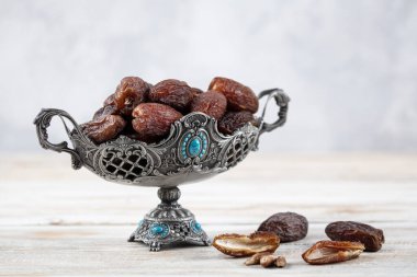 Tahta arka planda eski gümüş tabakta meyve ve zamzam suyu var. Ramazan iftar yemeği. Kurumuş tarihli Ramazan kareemi ve orjinal metal zamzam su testisi, kutsal ay konsepti..