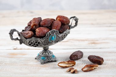 Tahta arka planda eski gümüş tabakta meyve ve zamzam suyu var. Ramazan iftar yemeği. Kurumuş tarihli Ramazan kareemi ve orjinal metal zamzam su testisi, kutsal ay konsepti..