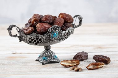 Tahta arka planda eski gümüş tabakta meyve ve zamzam suyu var. Ramazan iftar yemeği. Kurumuş tarihli Ramazan kareemi ve orjinal metal zamzam su testisi, kutsal ay konsepti..