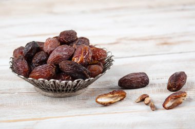 Tahta arka planda eski gümüş tabakta meyve ve zamzam suyu var. Ramazan iftar yemeği. Kurumuş tarihli Ramazan kareemi ve orjinal metal zamzam su testisi, kutsal ay konsepti..