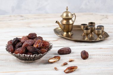 Tahta arka planda eski gümüş tabakta meyve ve zamzam suyu var. Ramazan iftar yemeği. Kurumuş tarihli Ramazan kareemi ve orjinal metal zamzam su testisi, kutsal ay konsepti..