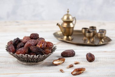 Tahta arka planda eski gümüş tabakta meyve ve zamzam suyu var. Ramazan iftar yemeği. Kurumuş tarihli Ramazan kareemi ve orjinal metal zamzam su testisi, kutsal ay konsepti..