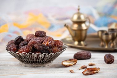 Tahta arka planda eski gümüş tabakta meyve ve zamzam suyu var. Ramazan iftar yemeği. Kurumuş tarihli Ramazan kareemi ve orjinal metal zamzam su testisi, kutsal ay konsepti..