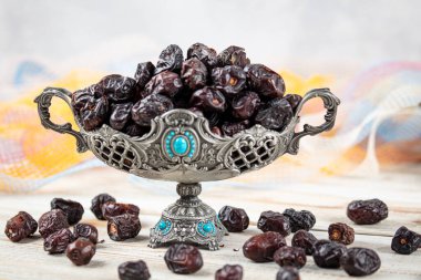 Acve hurma meyvesi, ahşap arka planda eski gümüş tabakta Acve palmiye meyvesi. Kurumuş meyve Ramazan Kareem, kutsal ay Ramazan kavramı.