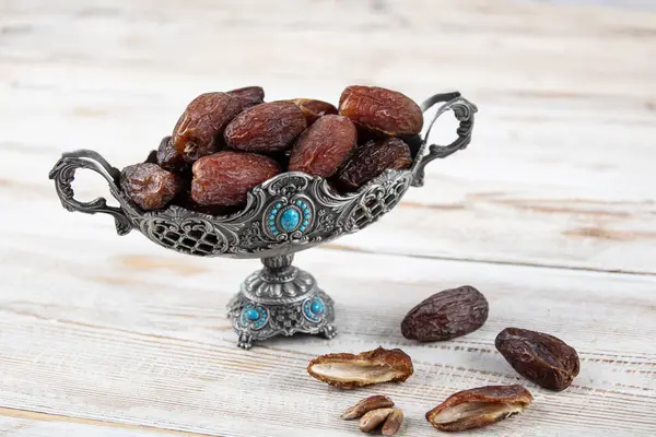 Tahta arka planda eski gümüş tabakta meyve ve zamzam suyu var. Ramazan iftar yemeği. Kurumuş tarihli Ramazan kareemi ve orjinal metal zamzam su testisi, kutsal ay konsepti..