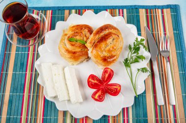 Geleneksel lezzetli peynirli Türk burek (Türk adı: Gül borek) Peynir, domates ve bir bardak çayla servis edilen peynirli hamur işi