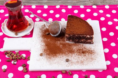 Tiramisu diliminin yan görüntüsü. Mermer tabakta kahve tozuyla süslenmiş tiramisu keki. Geleneksel İtalyan tatlısı. Kahve çekirdekleri, tekstil peçetesi, ahşap masa arka planı..