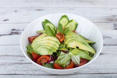 Beyaz tabakta taze avokado salatası. Yeşillik ve avokadoyla salatalık salatasını yakından izle..