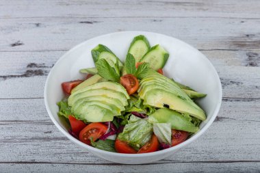 Beyaz tabakta taze avokado salatası. Yeşillik ve avokadoyla salatalık salatasını yakından izle..