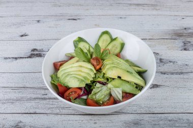 Beyaz tabakta taze avokado salatası. Yeşillik ve avokadoyla salatalık salatasını yakından izle..