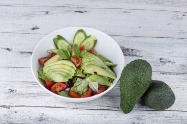Beyaz tabakta taze avokado salatası. Yeşillik ve avokadoyla salatalık salatasını yakından izle..