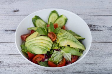 Beyaz tabakta taze avokado salatası. Yeşillik ve avokadoyla salatalık salatasını yakından izle..