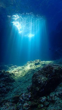 Artistic underwater photo of magic rays of sunlight inside a cave. From a scuba dive.