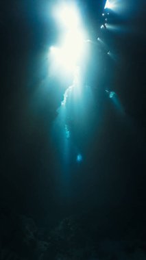 Bir mağaranın içindeki güneş ışınlarının sualtı fotoğrafı.