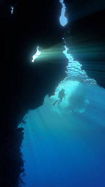 İçerideki mağara girişinde dalgıçla birlikte güneş ışınlarının sualtı fotoğrafı..