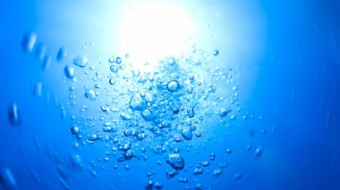 Hava kabarcıklarının su altında güneş ışığı ışınlarıyla yüzeye çıkışının sualtı fotoğrafı. Derin mavi okyanusta tüplü dalıştan.