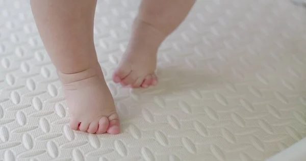 closeup little foot first step leg baby toddler on floor indoor home, happy child learning walking with barefoot, family childhood development