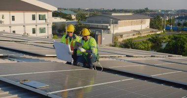 Analiz bakımını tartışan güvenlik yelekleri ve miğferler mühendisleri metal çatıya güneş panelleri kurarak sürdürülebilir enerji çözümlerini entegre ediyorlar.