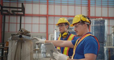 Üniformalı güvenlik ve tablet tutan işçi ortakları Metal İnşaat Üretim Fabrikası 'ndaki bir toplantıda konuşurken mühendisler endüstriyel projeleri tartışıyor. Takım çalışması.