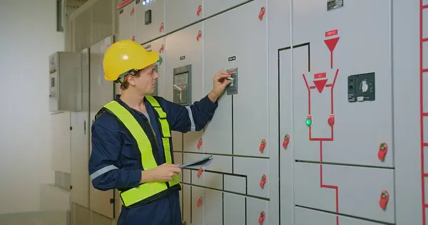 electricians electrical engineer in protective uniform wearing hard hat checking voltage control panel system at electrical cabinet for generate electricity of factory in manufacture industrial