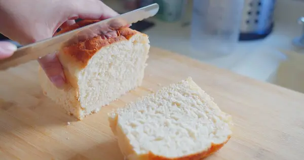 Bir insan tahta bir kesme tahtasıyla bir parça ekmek kesiyor. Ekmek ikiye bölünmüş ve bıçak onu kesmek için kullanılıyor. Ekmek kesmek yaygın olduğu için, basitlik ve rutin kavramı