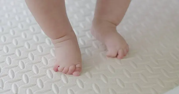 closeup little foot first step leg baby toddler on floor indoor home, happy child learning walking with barefoot, family childhood development