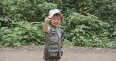 Mutlu küçük Asyalı turist kız çocuğu yağmur ormanlarında doğayı öğreniyor. Doğal arka plan, macera kaşifi kamp gezisi.