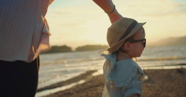 Mutlu Asyalı Aile Aşkı annesi, kızının elini tutuyor ve kumsalda yürüyor. Golden Hour neşe günbatımında birlikte kumsalda. Kıymetli Sunset Beach Moment 'ı paylaşın.