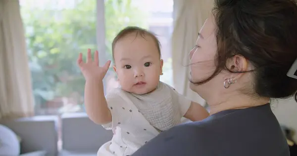 stock image Close up portrait young mother hold in arms hug cuddle little baby girl cute little infant toddler, loving Asian mom hug embrace small baby child, relax enjoy tender family moment Motherhood concept