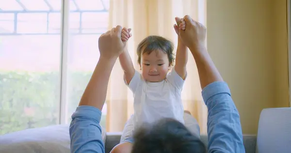 stock image A happy Joyful child playing with father on a couch in living room. dad holding little kid bonding together lounge on sofa enjoy lifestyle activity spend leisure time with parent at home