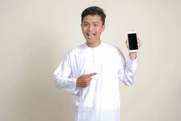 形象迷人的亚洲穆斯林男子穿着白衬衫 展示和展示空白屏幕手机 广告概念 灰度上的孤立图像 — 图库照片