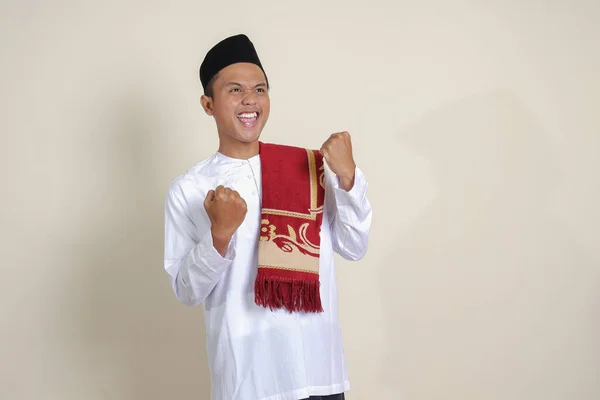 白いシャツを着た魅力的なアジア系イスラム教徒の男性の肖像画は 彼の拳を上げ 成功を祝う 灰色の背景に孤立した画像 — ストック写真