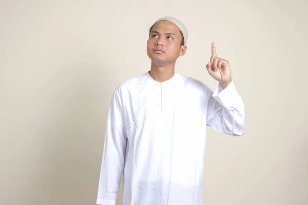 一位有魅力的亚洲穆斯林男子穿着白衬衫 用食指指尖着他的食指 提醒他该做些什么 广告概念 灰色背景上的孤立图像 — 图库照片