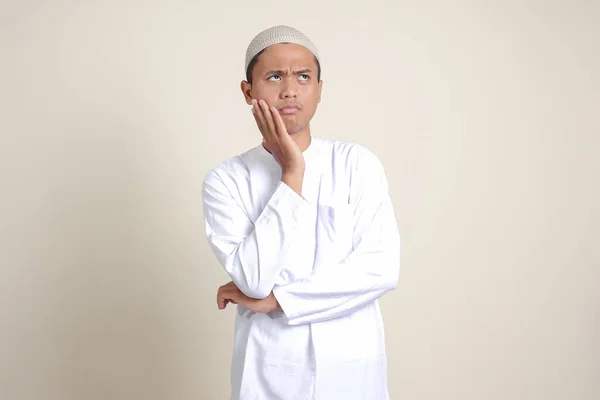 一位身穿白衬衫的有魅力的亚洲穆斯林男子的画像 手托着下巴思考着问题 灰色背景上的孤立图像 — 图库照片