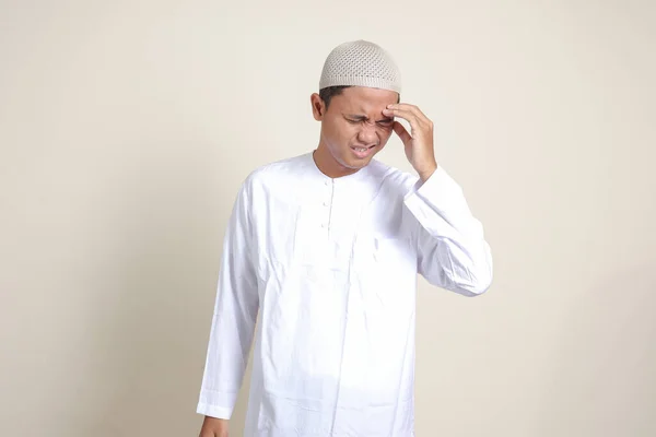 亚洲有魅力的穆斯林男子的画像 穿着白衬衫 患有偏头痛 摸着他的太阳穴 头痛的概念 灰色背景上的孤立图像 — 图库照片