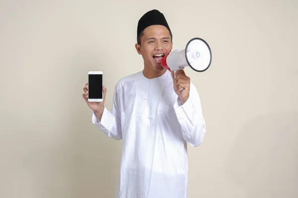 亚洲有魅力的穆斯林男子穿着白衬衫 一边用扩音器大声说话 一边展示和展示空白屏幕手机的肖像 广告概念 灰度上的孤立图像 — 图库照片