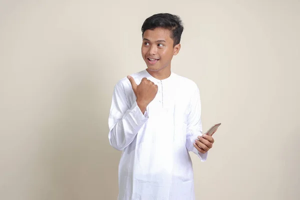 셔츠를 핸드폰을 웃으면서 손가락으로 가리키는 아시아 남성의 배경의 고립된 이미지 — 스톡 사진