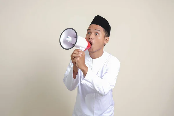 有魅力的亚洲穆斯林男子的画像 穿着白衬衫 头戴小帽 用扩音器大声说话 促销产品 广告概念 灰色背景上的孤立图像 — 图库照片