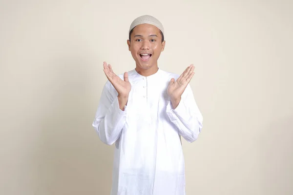 迷人的亚洲穆斯林男子的画像 身穿白衬衫 手拉手对着相机 邀请人进来 欢迎大家的手势 灰色背景上的孤立图像 — 图库照片
