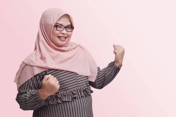 ヒジャーブを持つ陽気なアジアの女性の肖像画は 彼の拳を上げ 成功を祝う 広告コンセプト ピンクの背景に隔離された画像 — ストック写真