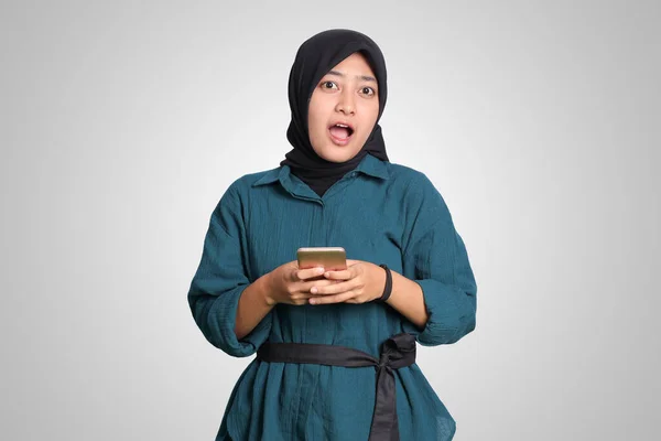 携帯電話を見てヒジャーブを持つショックを受けたアジア系ムスリム女性の肖像 うわー顔の表情 広告コンセプト 白い背景に孤立したイメージ — ストック写真