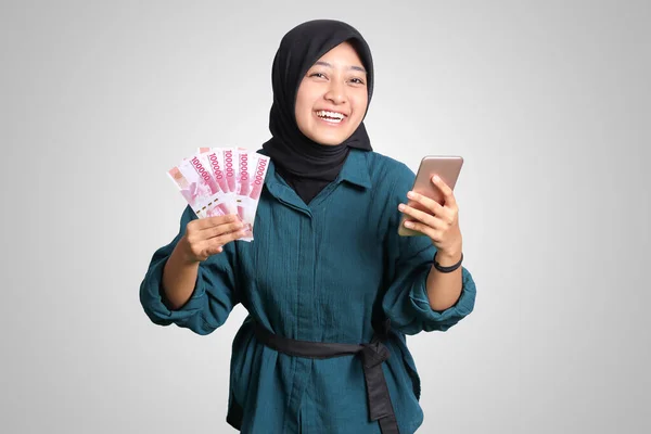 身穿休闲装的兴奋的亚洲头巾女人的画像 手持手机时显示出10万卢比 金融和储蓄概念 白色背景上的孤立图像 — 图库照片