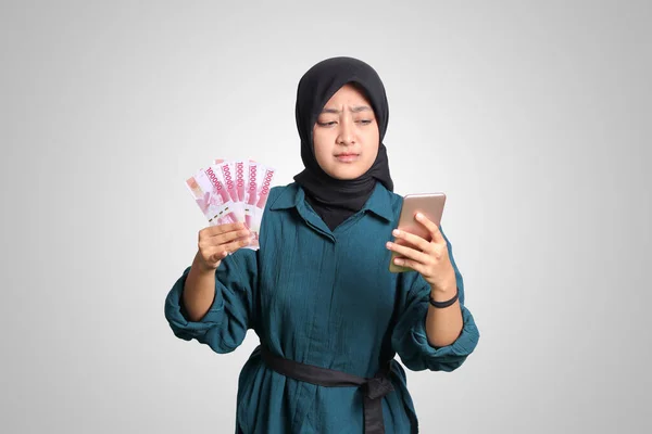 身穿休闲装的兴奋的亚洲头巾女人的画像 手持手机时显示出10万卢比 金融和储蓄概念 白色背景上的孤立图像 — 图库照片