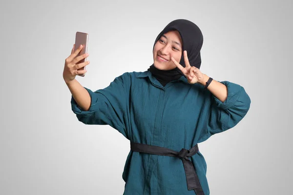 带头巾的兴奋的亚洲穆斯林妇女手持手机在视频通话时的肖像 并以手势打招呼 广告概念 白色背景上的孤立图像 — 图库照片