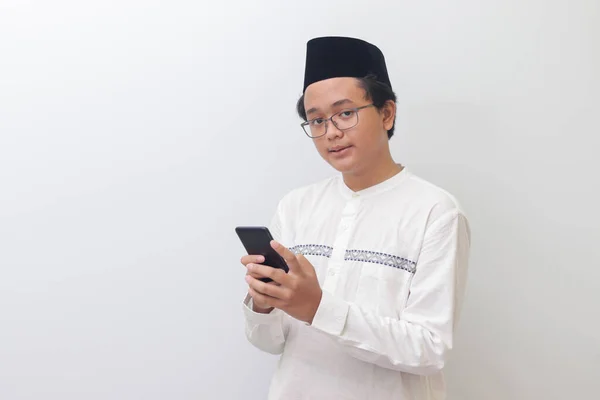 年轻的亚洲穆斯林男子面带微笑地拿着手机的画像 白色背景上的孤立图像 — 图库照片