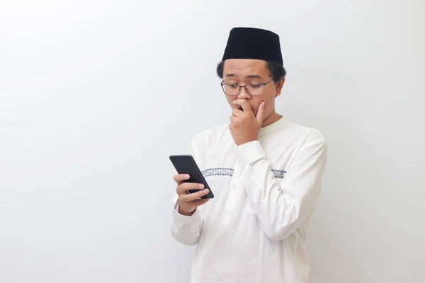 年轻的亚洲穆斯林男子手持手机 满嘴震惊表情的画像 白色背景上的孤立图像 — 图库照片
