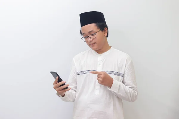 年轻而兴奋的亚洲穆斯林男子在使用手机时用手指指尖的肖像 白色背景上的孤立图像 — 图库照片